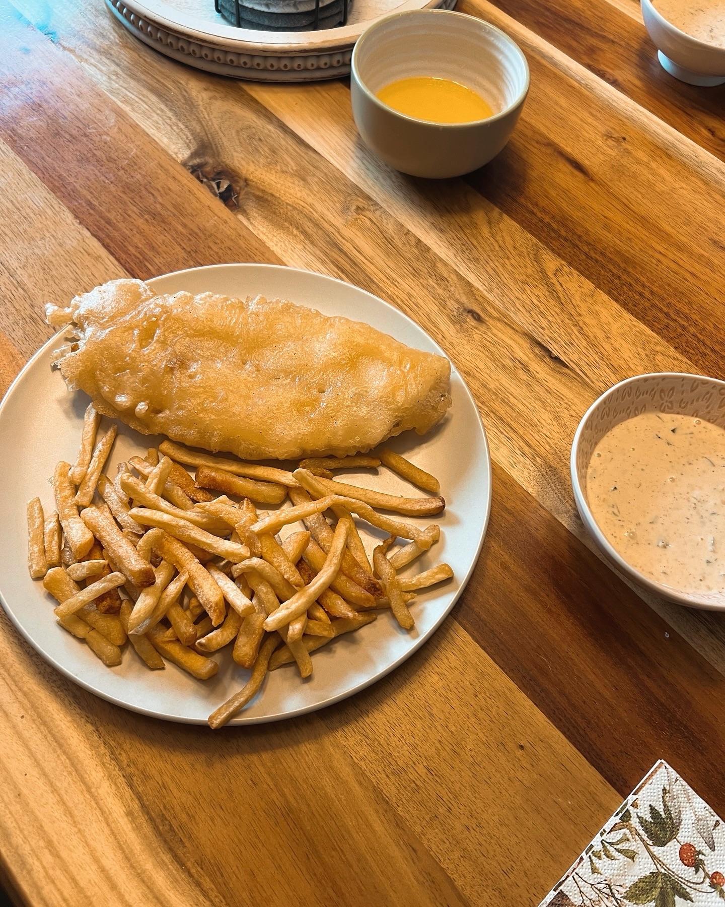 Beer-battered walleye and fries plated on a wooden table