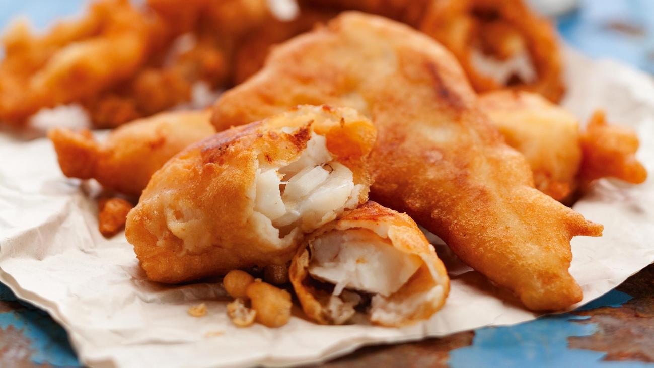 Close-up of beer-battered fish broken open showing flaky white fish inside crispy batter