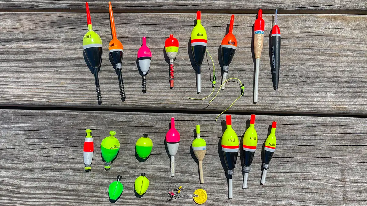 A wide selection of fishing floats and bobbers laid out on a wooden dock